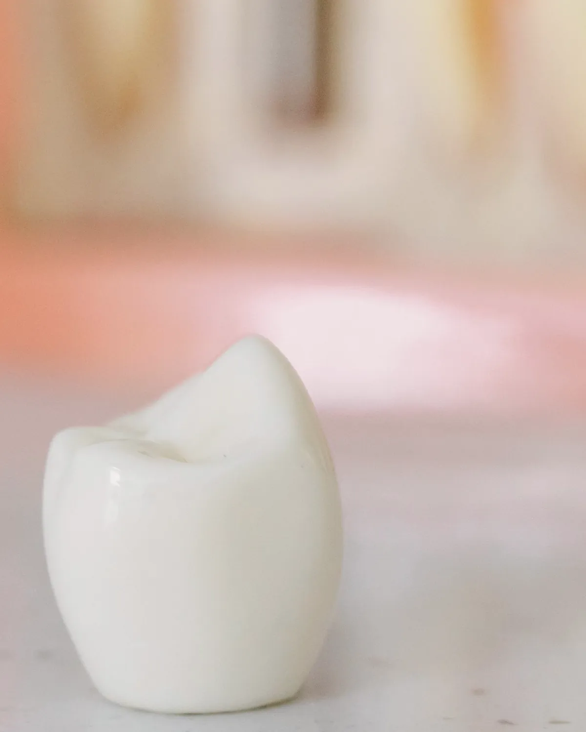 A single white dental crown in front of a tooth model